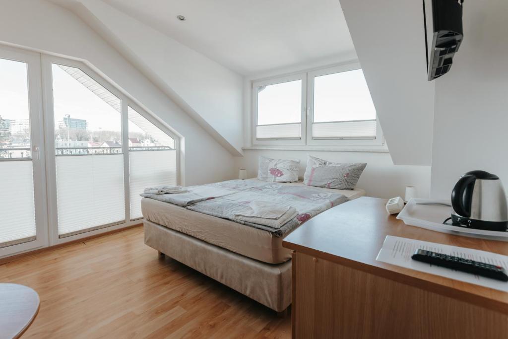 a bedroom with a bed and a desk and windows at Willa Sarenka in Międzyzdroje