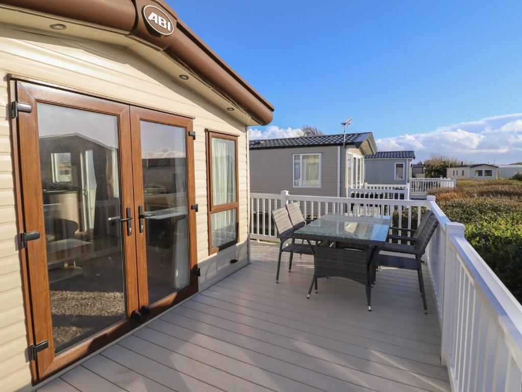 a deck with a table and chairs on a house at 23 Gull Court in Porthmadog