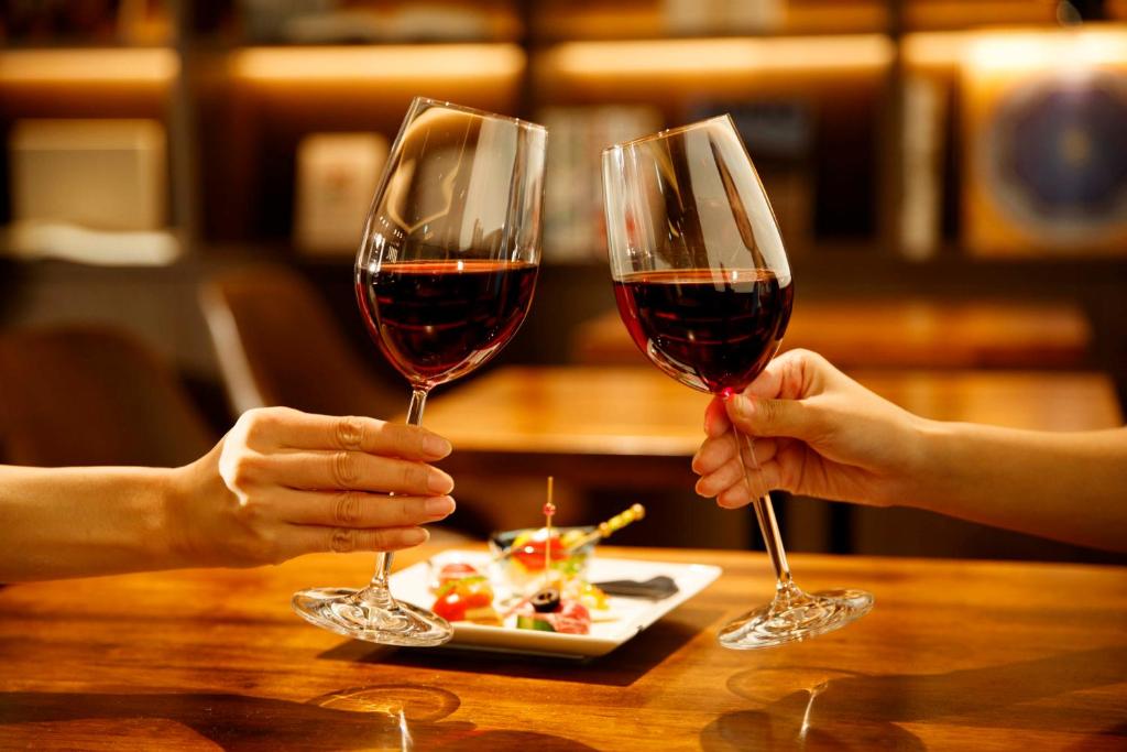 two people holding up glasses of red wine at Royal Park Hotel Takamatsu in Takamatsu