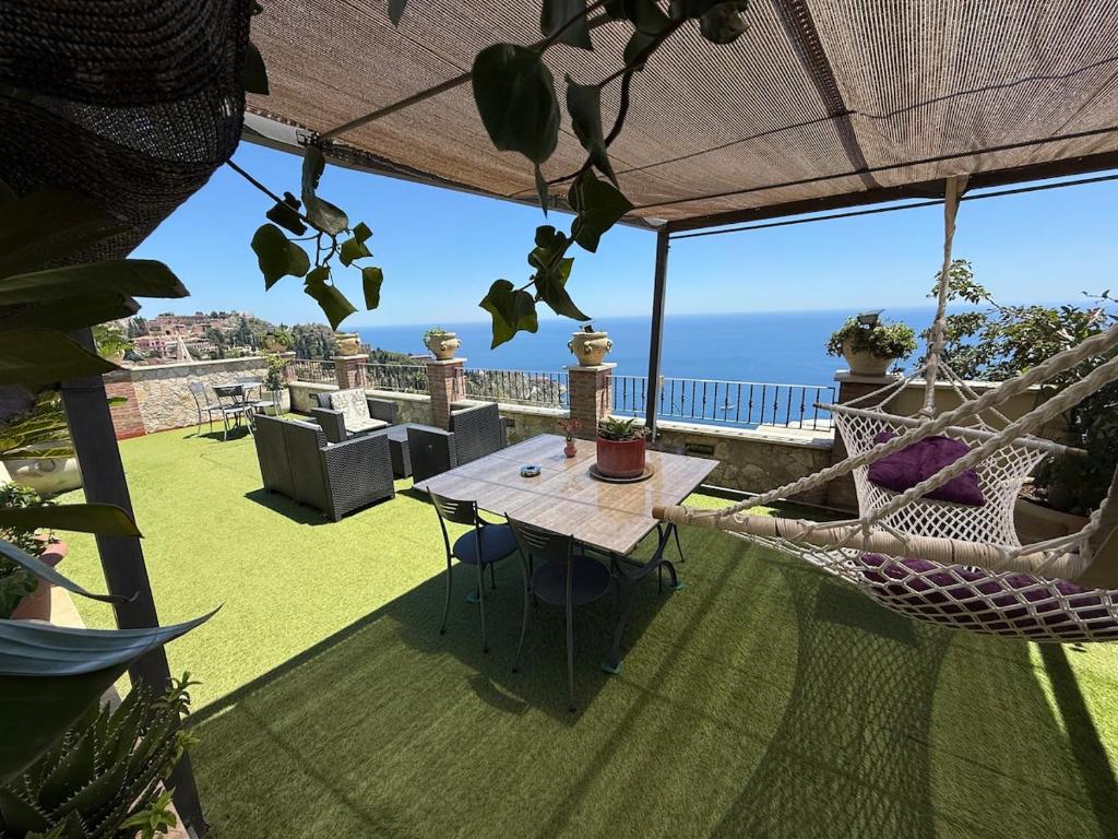 a hammock and a table on a balcony with the ocean at Casa Bucalo 2, Taormina in Taormina