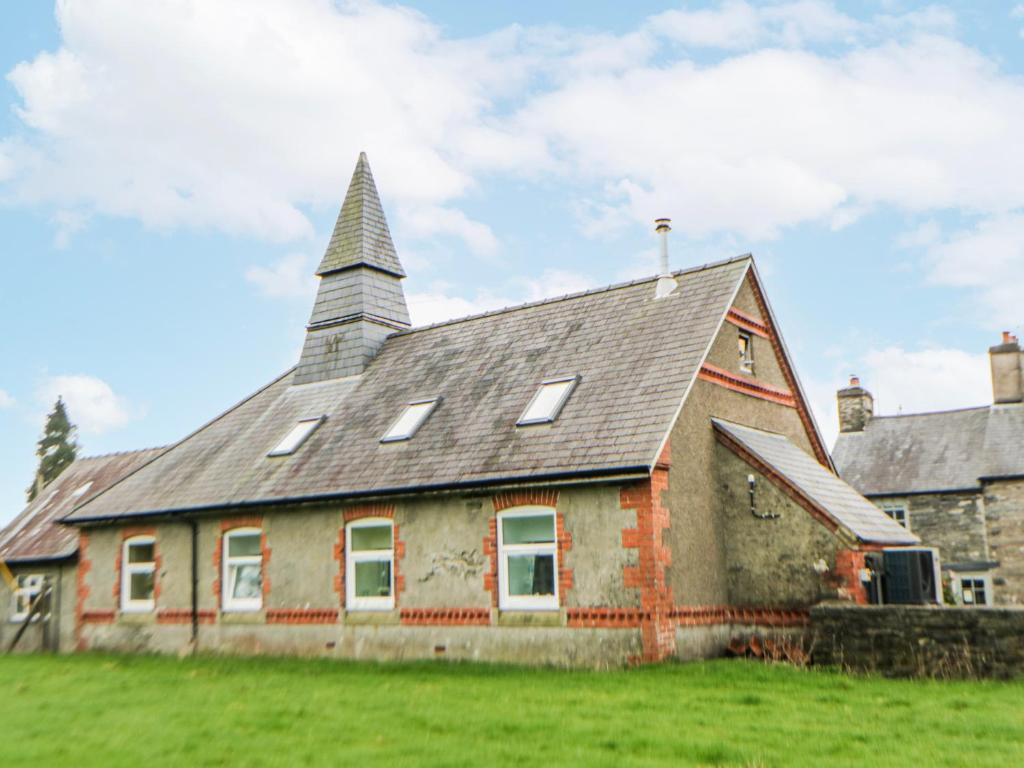an old house with a steeple on top of a field at Yr Hen Ysgoldy in Machynlleth