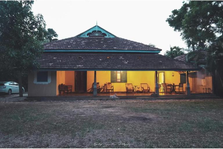 a yellow house with a porch with chairs on it at Catumaran Jaffna in Jaffna