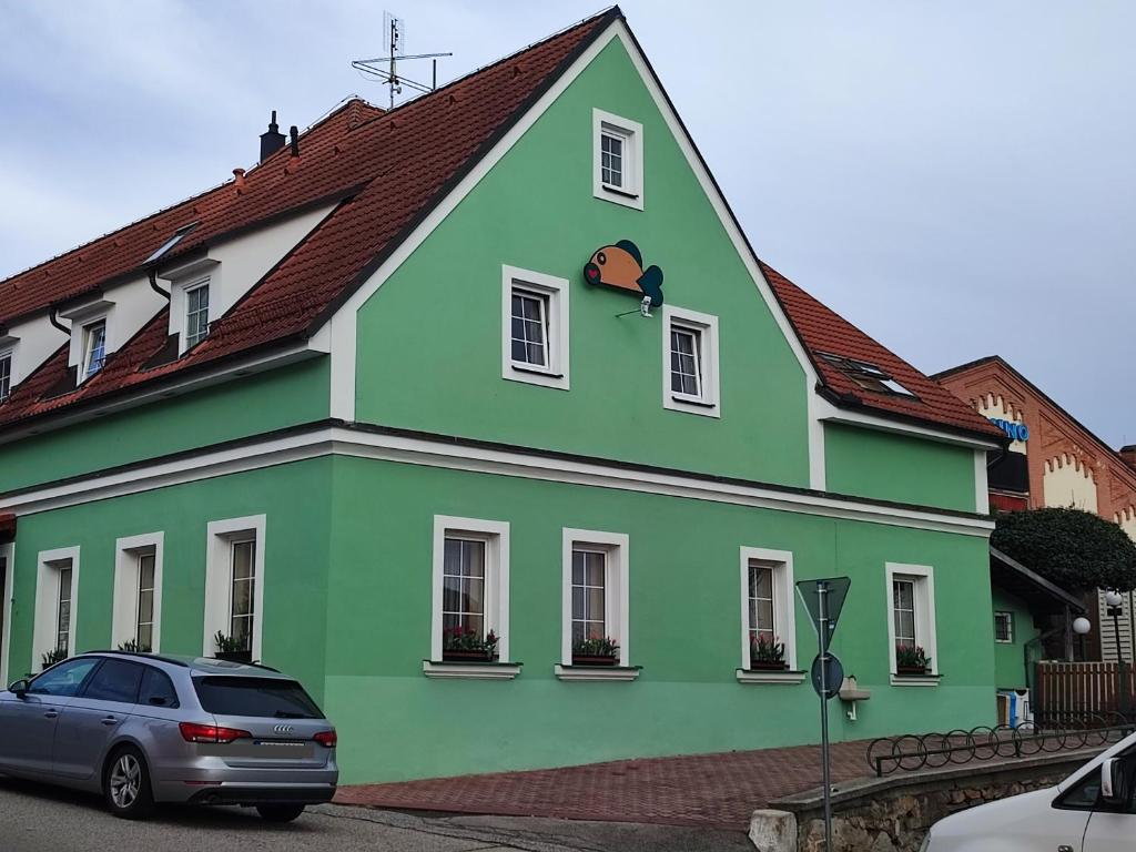 a green house with a car parked in front of it at Pension KA.PR in Hluboká nad Vltavou