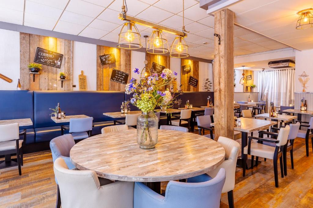 a restaurant with tables and chairs and a table with flowers at Hotel de Burg in Domburg