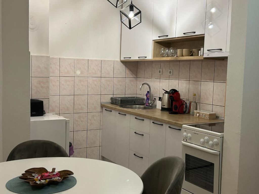a kitchen with white cabinets and a table with chairs at Paradiso 5 in Bratunac