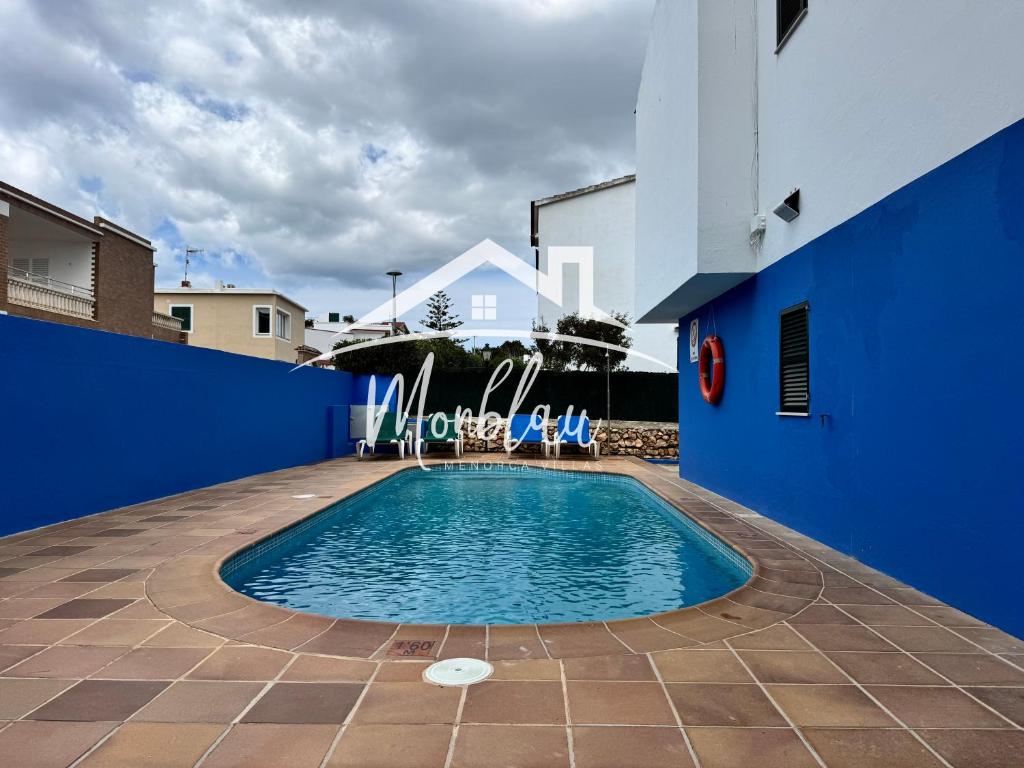 a swimming pool in the courtyard of a blue building at Sa Torreta 4 in Cala Blanca