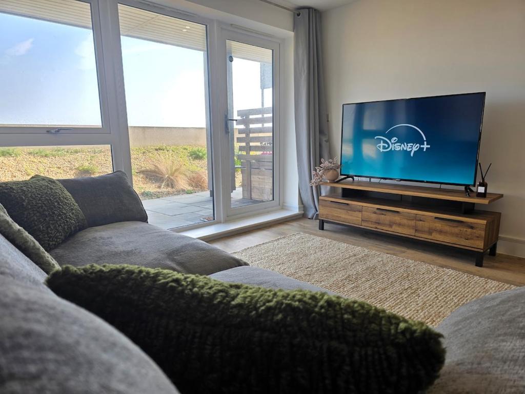 a living room with a couch and a flat screen tv at Littlestone Seaside Retreat in Littlestone-on-Sea