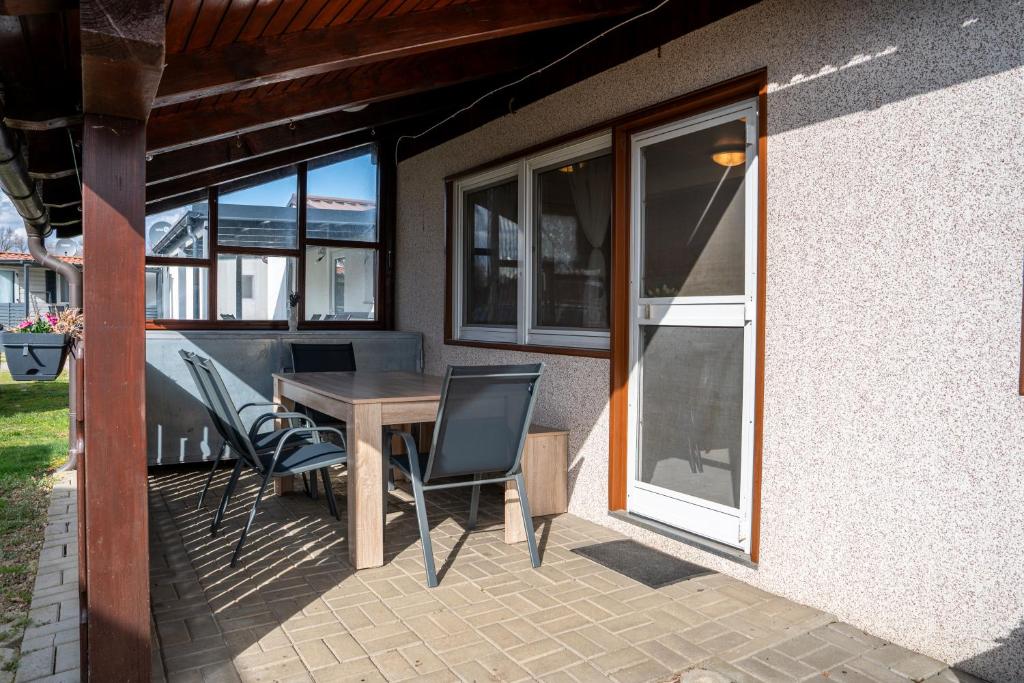 a patio with a table and chairs and windows at Hiška 231, 2 karti za Terme 3000, Moravske Toplice in Moravske-Toplice