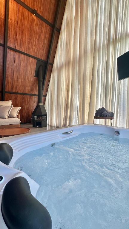 a large hot tub in a room with a fireplace at Chalé Rio das Pedras - Chalé 03 in Chapecó