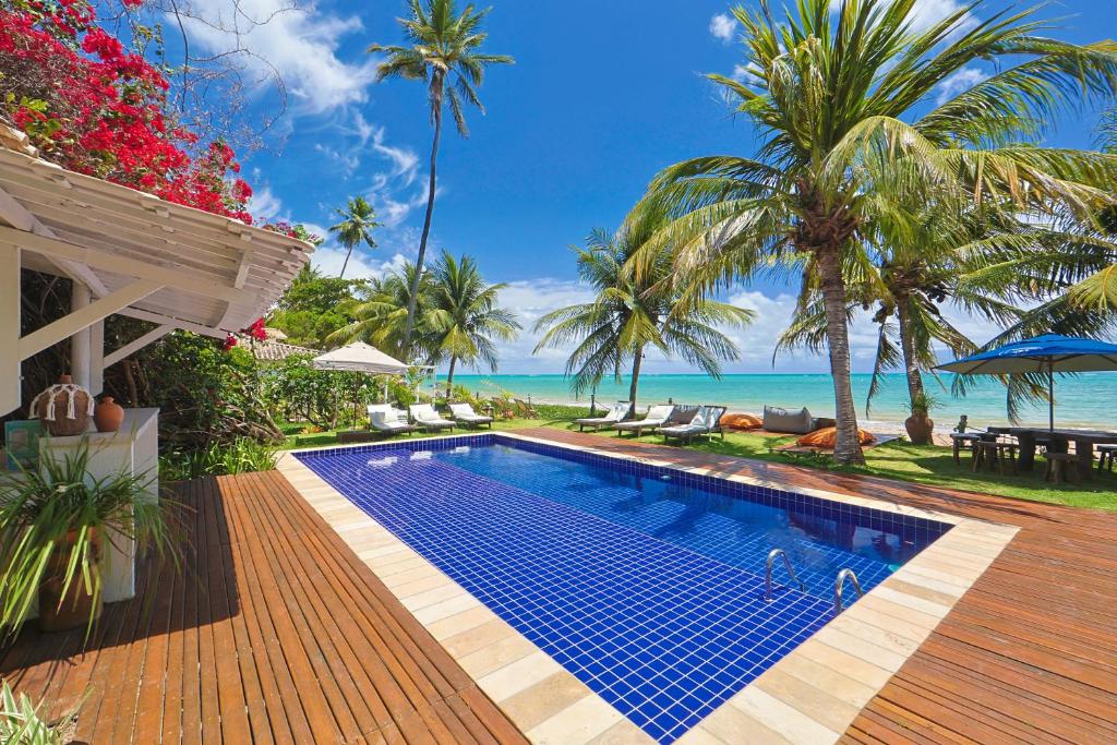 a swimming pool on a wooden deck next to the ocean at Estalagem Caiuia in Japaratinga