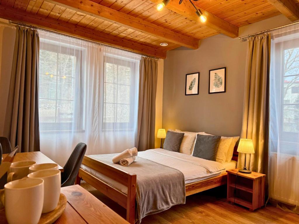 a bedroom with a bed and a table and windows at Willa Maya in Karpacz