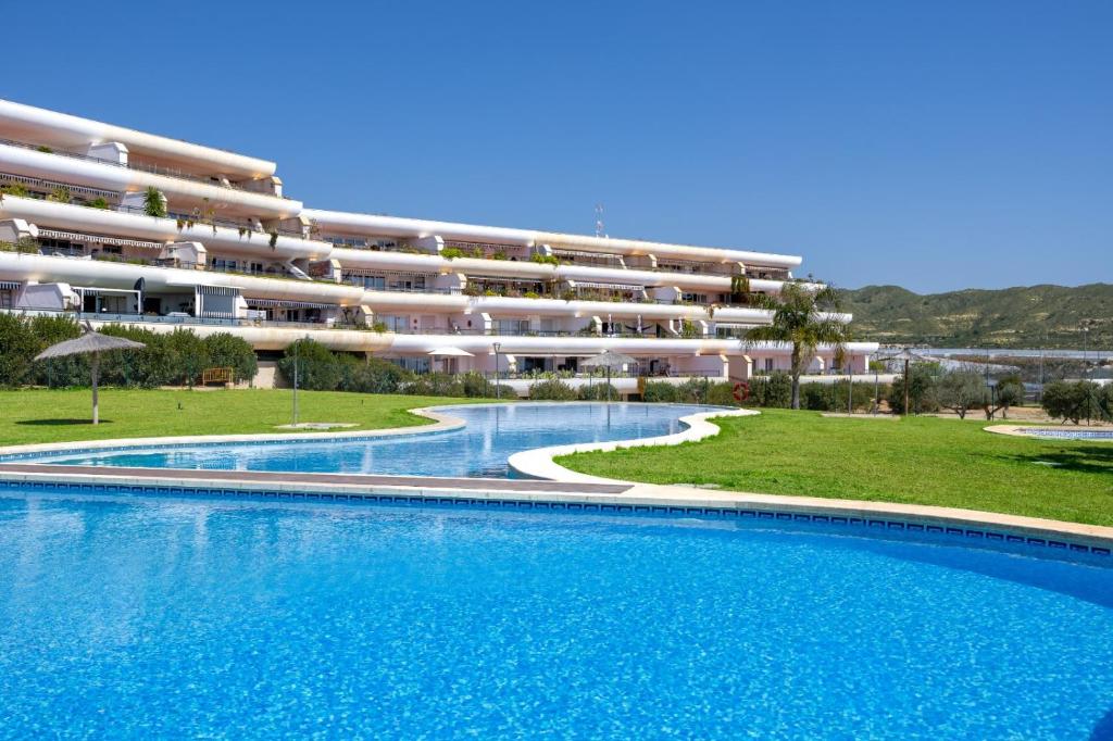a swimming pool in front of a large apartment building at Mediterranean & golf dreams in Alicante