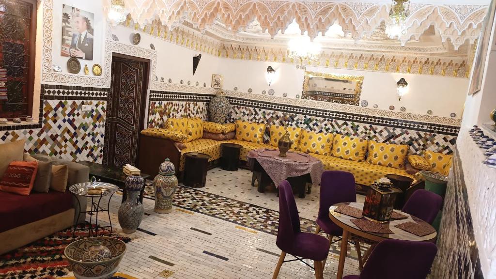 ein Wohnzimmer mit Sofa, Tisch und Stühlen in der Unterkunft Riad Dalal in Fès