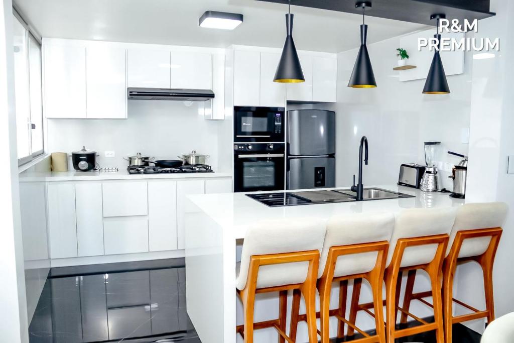 a kitchen with white cabinets and a bar with stools at R&M Premium in Baños