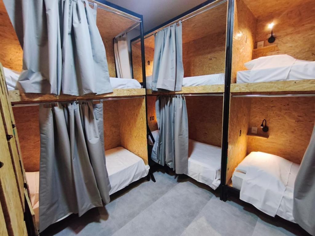 a room with three bunk beds and a mirror at Hostel Vila Universitária in Bauru