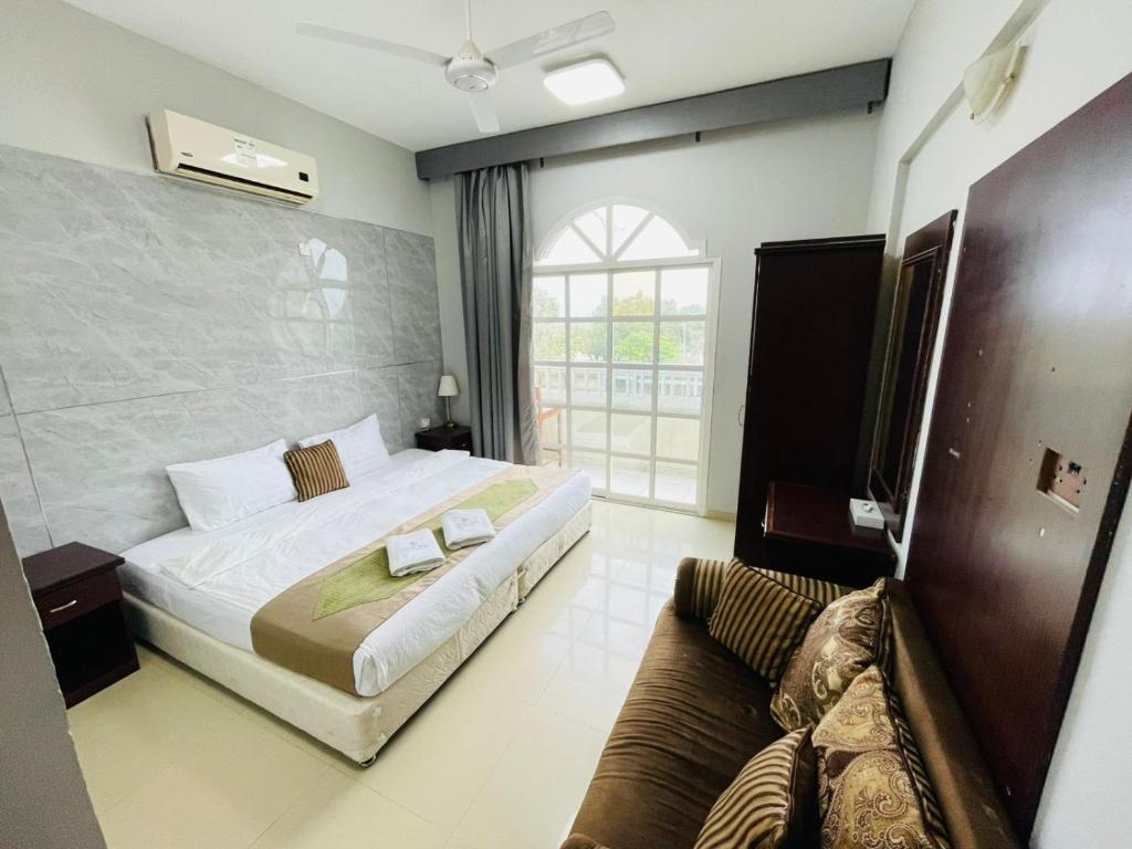 a hotel room with a bed and a couch at Cozy 1 Bedroom Hall in Khor Fakkan