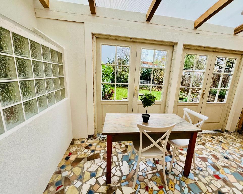 a table and chairs in a room with windows at MAISON privée, La glycine blanche, a 10min de Strasbourg in Schiltigheim