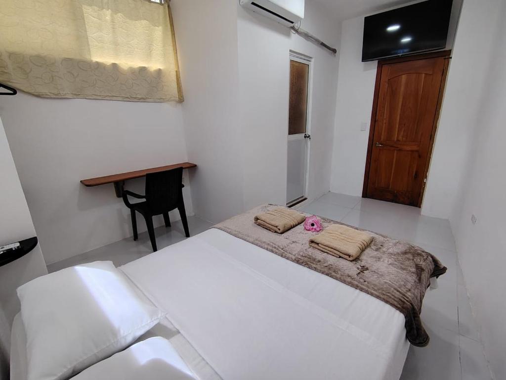 a white bedroom with a bed and a desk at Galápagos Finch Apartment in Puerto Ayora