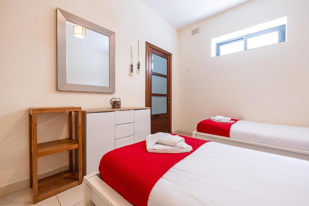 a bedroom with two beds and a mirror at Mandalay Cozy & Affordable Apartment with Patio in Mellieħa