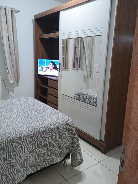 a bedroom with a bed and a flat screen tv at Casa da nicinha in Vitória