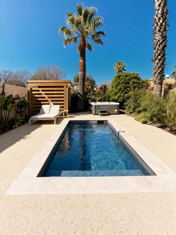 a swimming pool in a backyard with a bench and palm trees at Villa Clemarine - Piscine & Jacuzzi in Sanary-sur-Mer