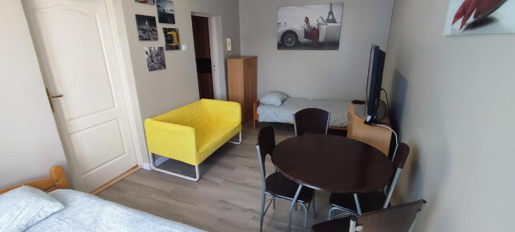 a living room with a table and a yellow chair at Noclegi Włocławek in Włocławek