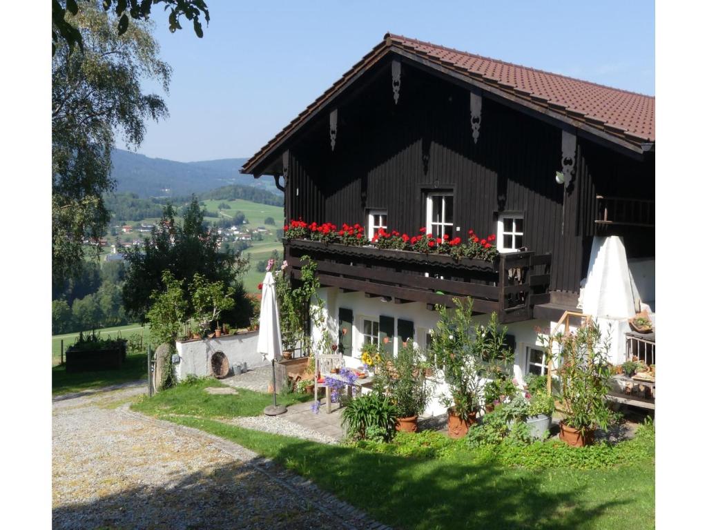 a black and white house with red flowers on the balcony at Ferienhaus in Kollnburg mit Garten in Achslach