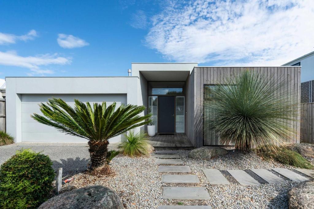 a house with a palm tree in front of it at Super-Styled Light-Filled Eco Home in Torquay