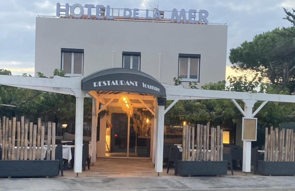a restaurant with tables and chairs in front of a building at Hôtel de la Mer - Barcarès, à 100 m de la plage in Le Barcarès