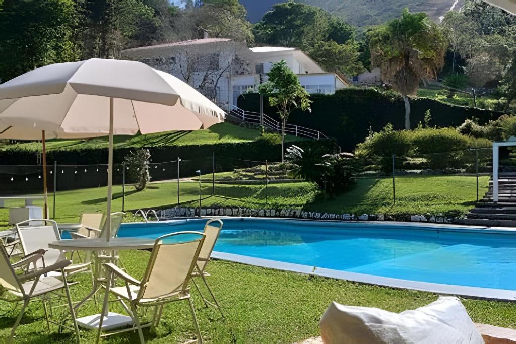 a group of chairs and an umbrella next to a pool at Sítio p/ Casamentos 8 min do Centro de Petrópolis in Petrópolis