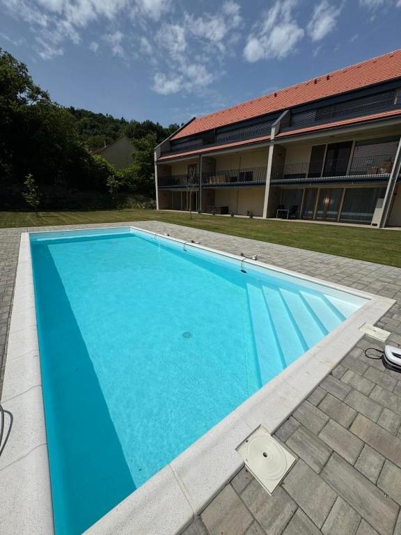 a large blue swimming pool in front of a building at Vinopool Suites Badacsony in Badacsonytomaj