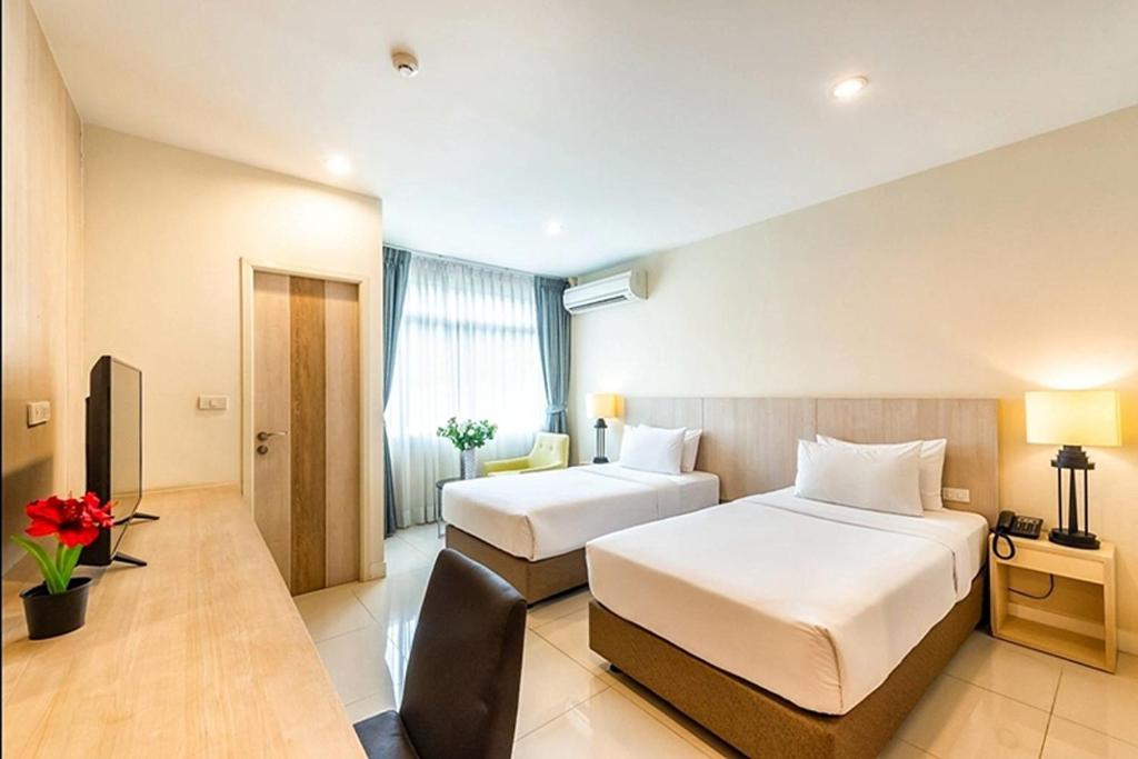 a hotel room with two beds and a television at Paeva Luxury By Nakra Functionality in Bang Bo