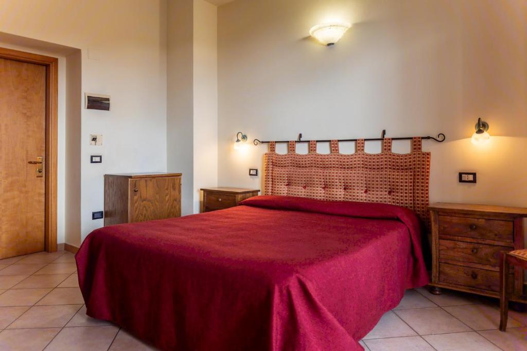 a bedroom with a large bed with a red blanket at Hotel Rossi in Manciano