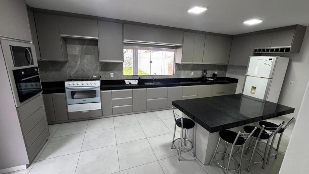 a kitchen with gray cabinets and a black counter top at Casa Aparecida in Uberlândia