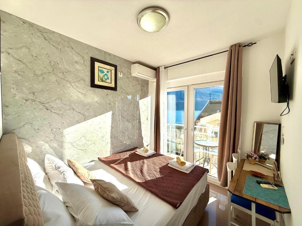a bedroom with a bed and a large window at Beachfront Bliss in Đenovići