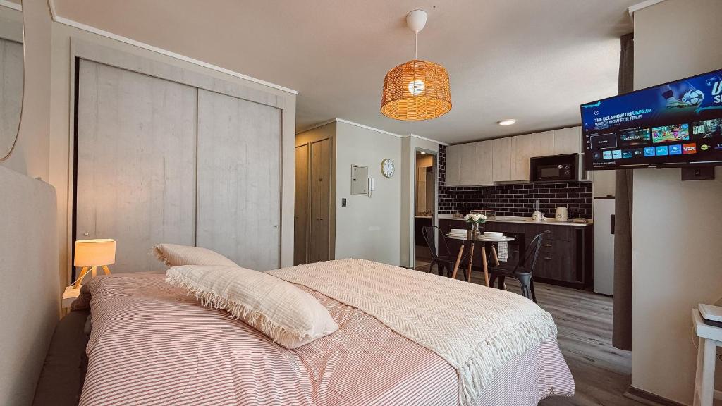 a bedroom with a bed and a tv and a kitchen at Getaway in Valparaiso in Valparaíso