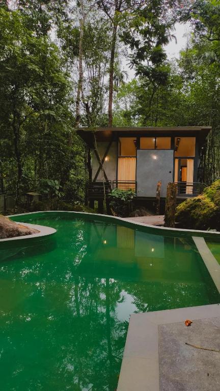a house with a pool of green water in front of it at ROCKs VILLA RESORT in Meppādi