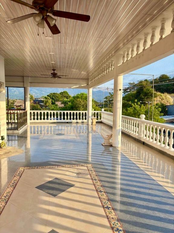 a large white porch with a ceiling fan and a balcony at Casa Raíces "Aire acondicionado, habitaciones familiares y económicas en La Dorada" in La Dorada