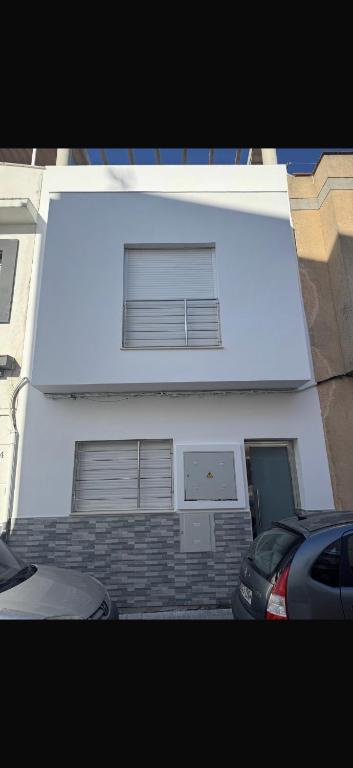 a white building with two windows and a car parked in front at Apartamento alhelí 2 in Barbate