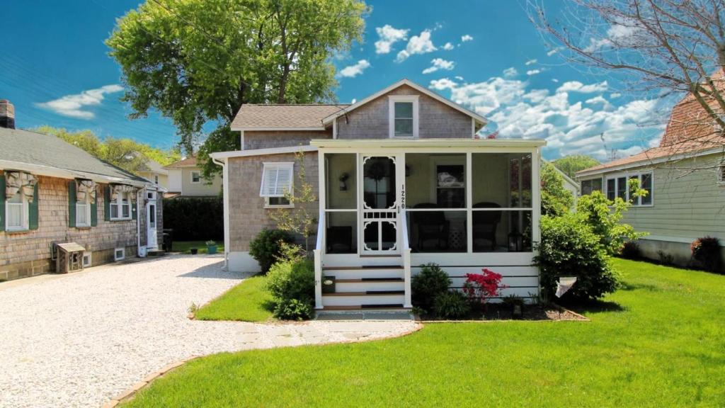 a house with a white front door and green grass at Little Cottage On Lafayette in Cape May