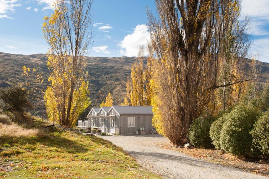 a house on the side of a road with trees at Gibbston Boathouse with Outdoor Bath in Gibbston