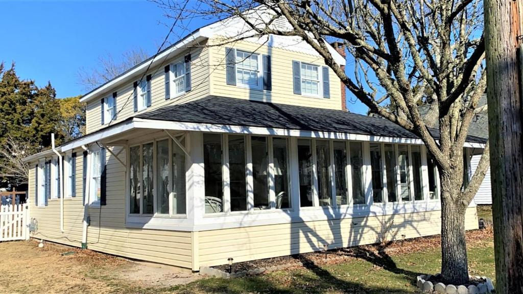 a yellow house with white windows and a tree at 409 Princeton in Cape May Point
