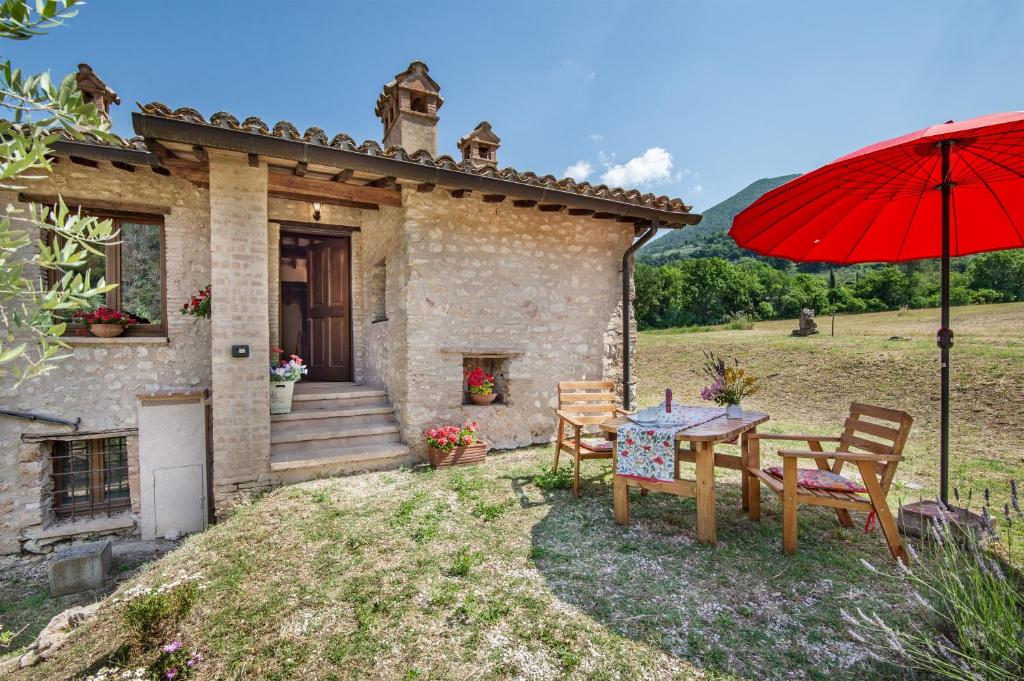 a house with a table and a red umbrella at Casaletto ''La Lavanda'' in Bazzano Inferiore