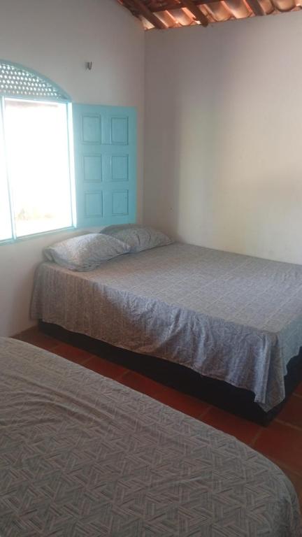 a bedroom with two beds and a window at Casa bela vista in Icapuí