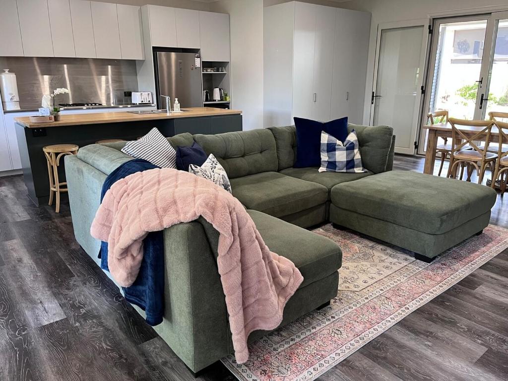 a living room with a green couch and a kitchen at Hathaway House in Toowoomba