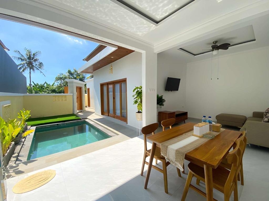 a living room with a table and a swimming pool at Villa Sinyo By Mentaripro Bali in Lovina