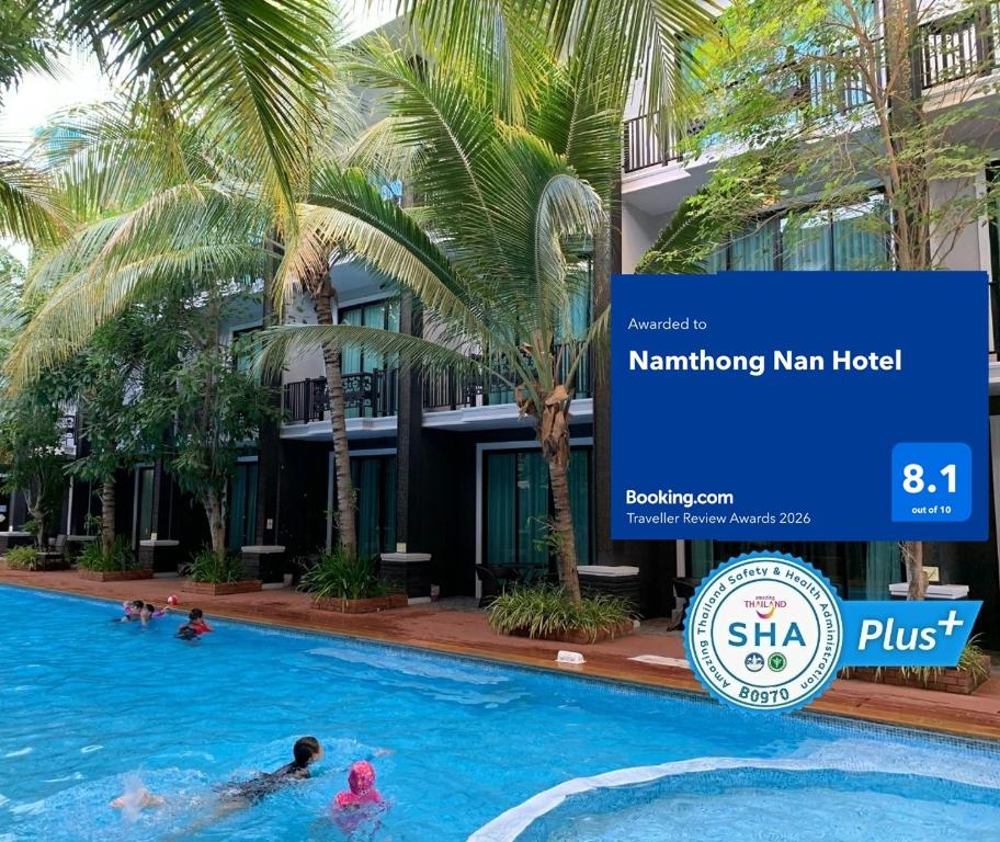 a swimming pool in front of a building with palm trees at Namthong Nan Hotel in Nan