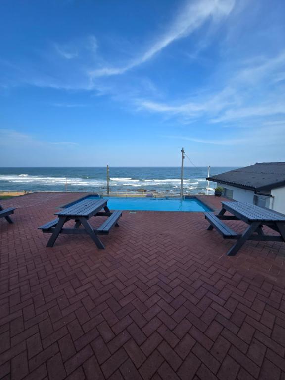 two picnic tables sitting on a brick patio near the ocean at Umdloti Luxe Horizon in Umdloti
