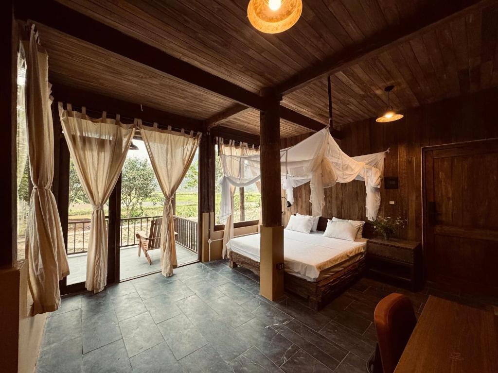 a bedroom with a canopy bed and a balcony at Nabum Retreat in Làng Giang