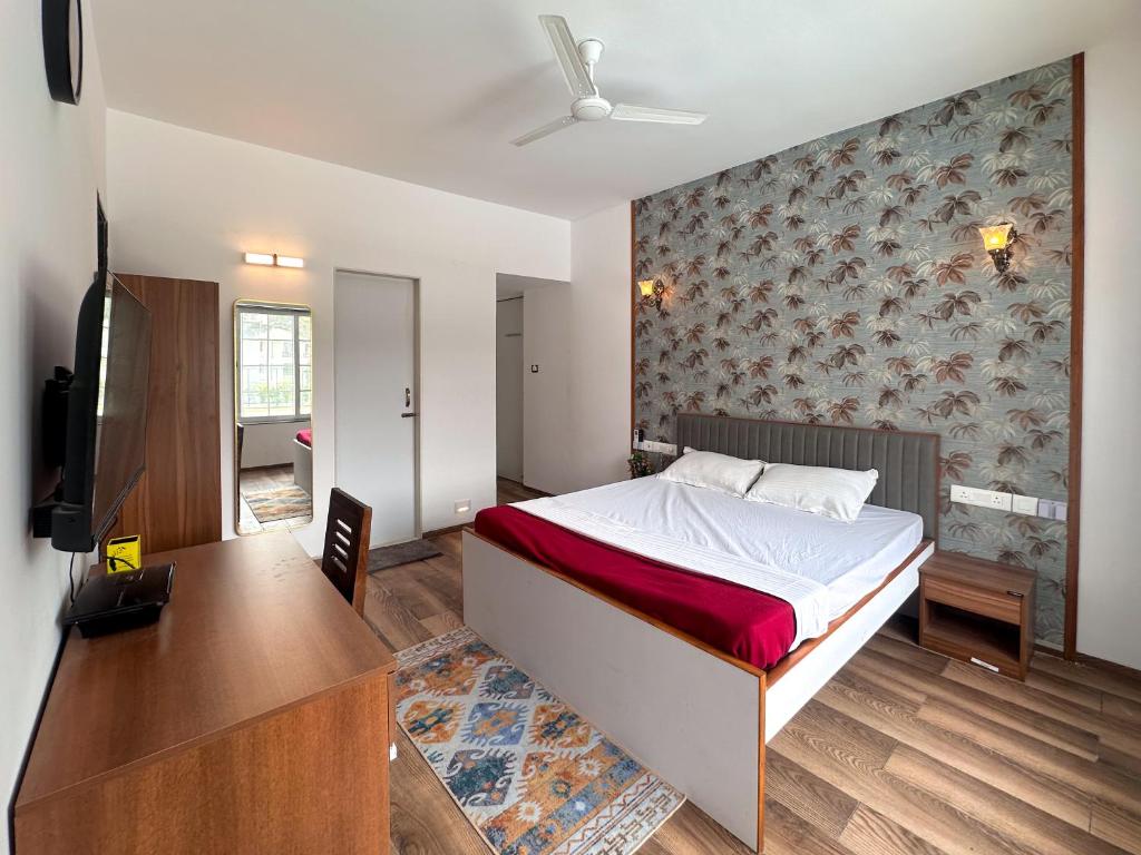 a bedroom with a bed and a desk and a television at NIVANTA-CREAZE by Bendre's in Kārli